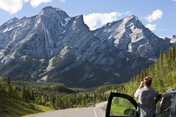 man standing by car looking at mountain on Icefields Parkway